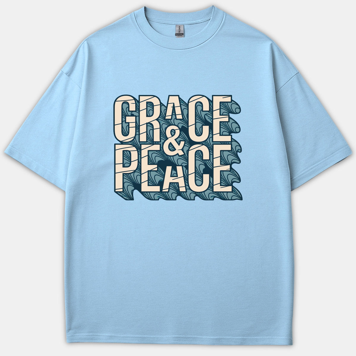 A light blue Christian t-shirt featuring the graphic text 'GRACE & PEACE' in off-white block lettering with a dark blue wave drop shadow pattern.