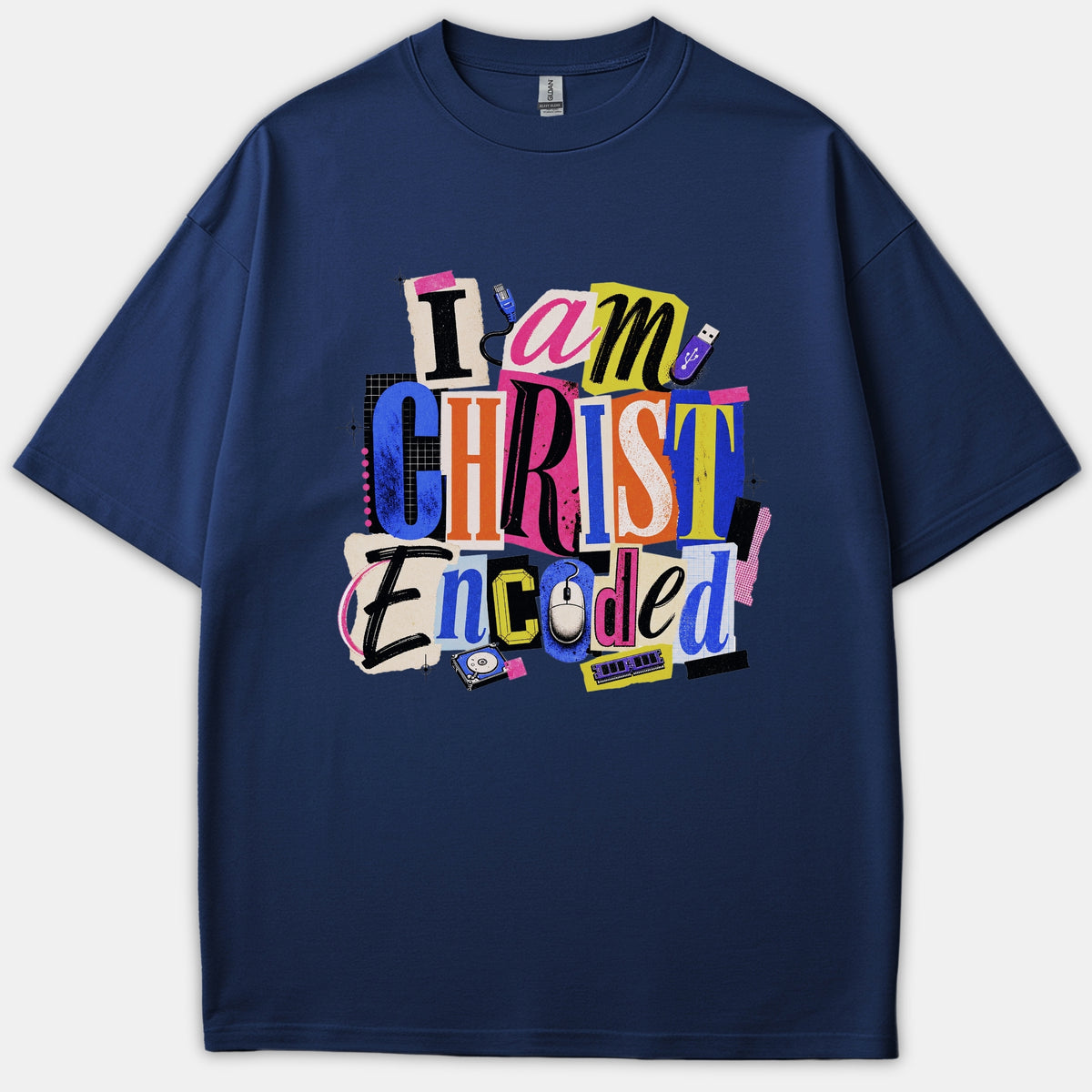 A navy blue t-shirt featuring a colorful collage graphic that reads 'I am CHRIST Encoded' in a cutout typography style paired with tech elements like a mouse and memory modules.