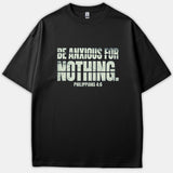 A black t-shirt featuring a bold, distressed typographic graphic on the chest that reads 'BE ANXIOUS FOR NOTHING. PHILIPPIANS 4:6'.