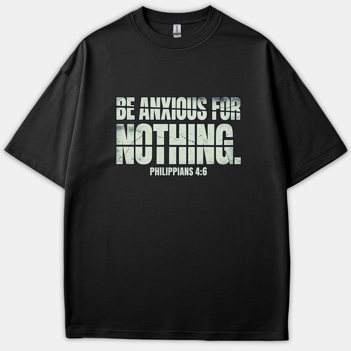 A black t-shirt featuring a bold, distressed typographic graphic on the chest that reads 'BE ANXIOUS FOR NOTHING. PHILIPPIANS 4:6'.