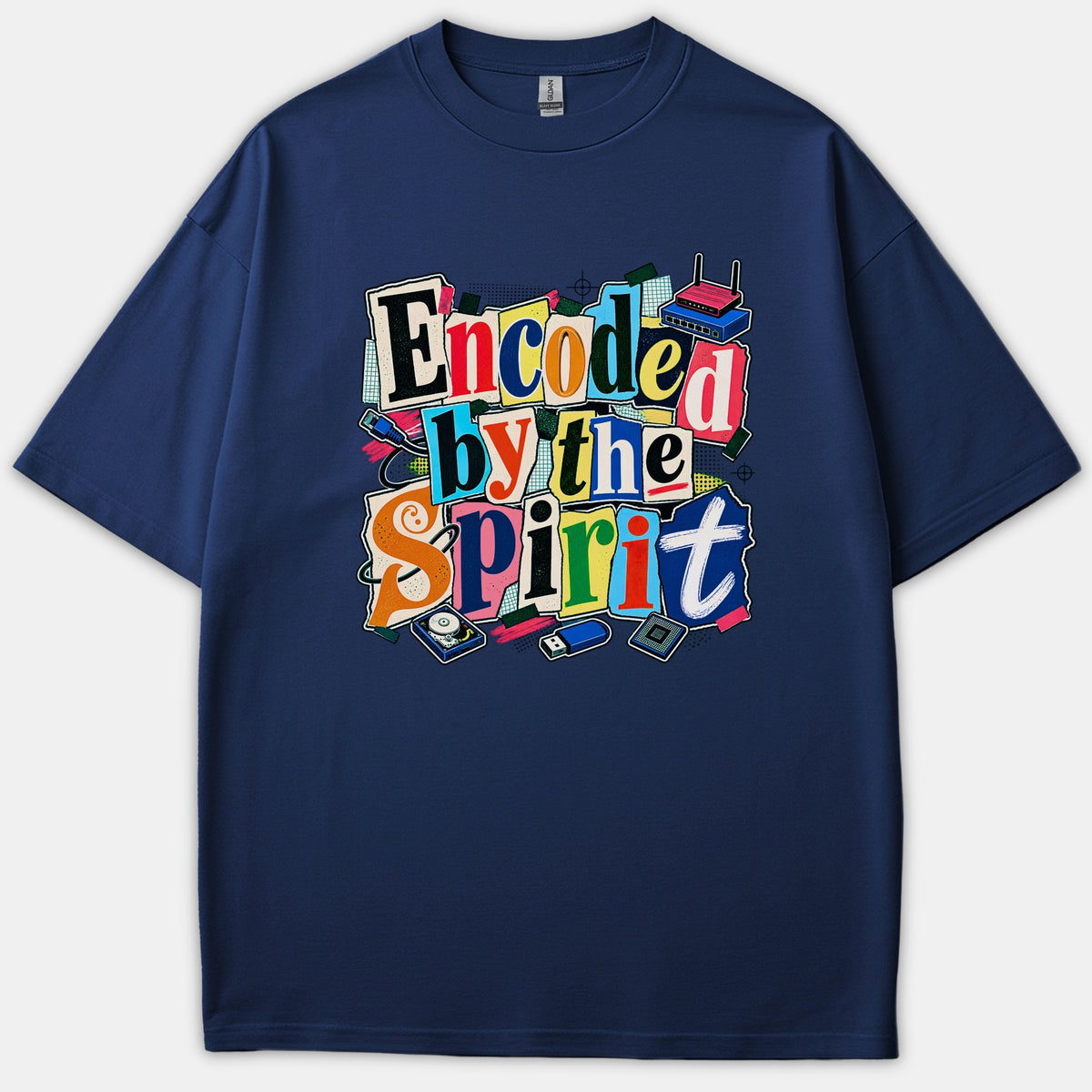 A navy blue t-shirt featuring a colorful ransom-note style graphic that reads Encoded by the Spirit surrounded by tech accessories like a router, hard drive, and USB drive.