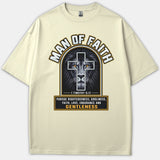 A beige Christian t-shirt featuring a graphic of a lion behind a cross with the words Man of Faith and 1 Timothy 6:11 scripture.