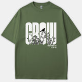 An olive green Christian t-shirt featuring the word GROW in bold white typography with black branch and bird silhouettes, alongside the Scripture reference Matthew 13 v.31-32.