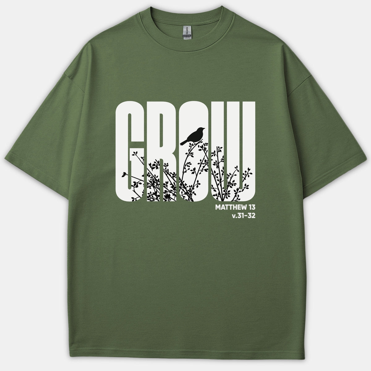 An olive green Christian t-shirt featuring the word GROW in bold white typography with black branch and bird silhouettes, alongside the Scripture reference Matthew 13 v.31-32.