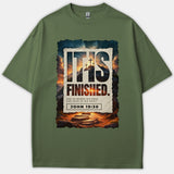 An olive green Christian t-shirt featuring a dramatic sunset graphic with three crosses, displaying the phrase 'IT IS FINISHED' and scripture reference John 19:30.