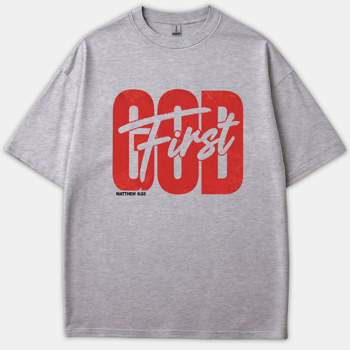 A gray Christian T-shirt featuring bold red text reading GOD layered with white script that says First, accompanied by the Bible verse Matthew 6:33 underneath.