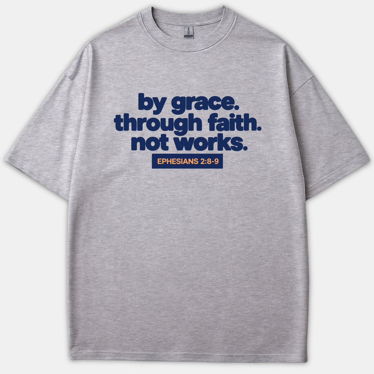 A heather gray t-shirt featuring navy bold text reading 'by grace. through faith. not works.' above a navy block with orange text that reads 'EPHESIANS 2:8-9'.
