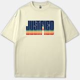 A beige t-shirt featuring the word JUSTIFIED in bold navy typography with colorful retro stripes across the chest.