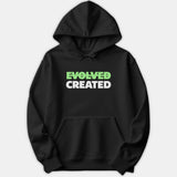A black hoodie featuring the word EVOLVED crossed out in green above the word CREATED printed in bold white text across the chest.