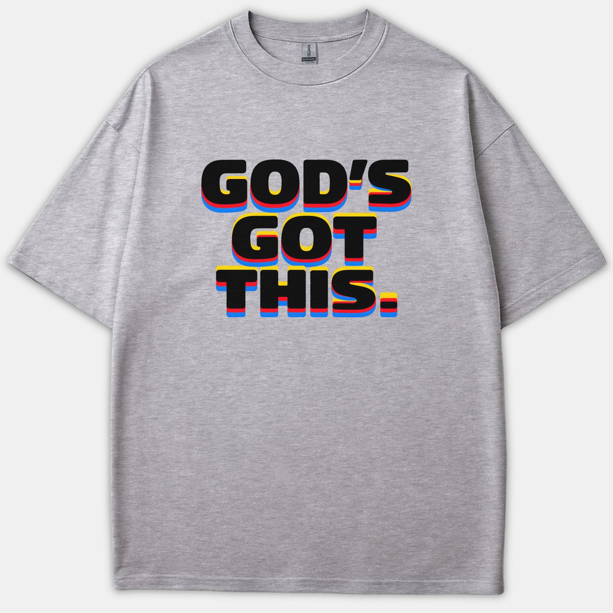 A gray graphic t-shirt featuring the bold phrase 'GOD'S GOT THIS.' in black lettering with colorful yellow, red, and blue layered drop shadow effects.