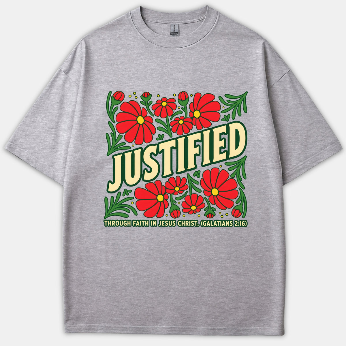 A heather gray T-shirt featuring a retro square print with red flowers, green leaves, and the text 'JUSTIFIED through faith in Jesus Christ (Galatians 2:16)'.
