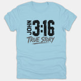 A light blue t-shirt featuring a distressed graphic that reads JOHN 3:16 in bold black text above the words TRUE STORY in brush-style gray font.