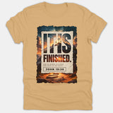 A beige Christian t-shirt featuring a framed graphic of a cross atop a hill with the text 'IT IS FINISHED' and Bible verse John 19:30.