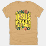 A beige Christian t-shirt featuring a retro floral design with the bold text 'Jesus Over Religion' surrounded by colorful flowers and leaves.
