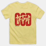 A pale yellow short-sleeve crewneck t-shirt featuring a distressed red graphic on the front that reads 'God First' with 'God' in a bold block font and 'First' in a script font, with 'MATTHEW 6:33' printed below.