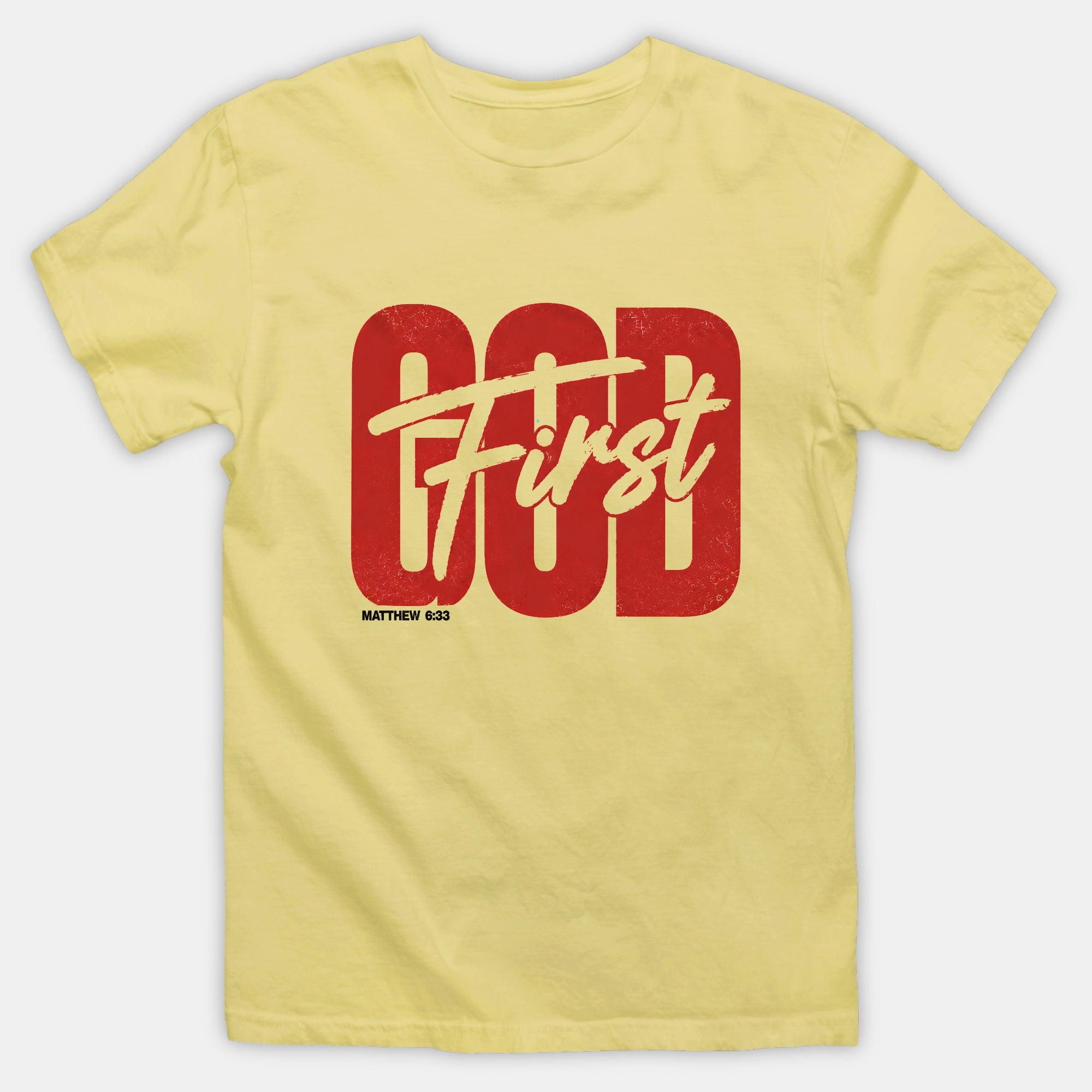 A pale yellow short-sleeve crewneck t-shirt featuring a distressed red graphic on the front that reads 'God First' with 'God' in a bold block font and 'First' in a script font, with 'MATTHEW 6:33' printed below.