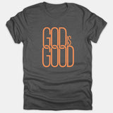 A dark gray t-shirt featuring a stylized orange graphic design on the chest reading GOD IS GOOD in an interlocking typography style.