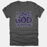 A gray Christian t-shirt featuring a distressed graphic that reads 'I OWE GOD EVERYTHING' printed in bold purple lettering with a green outline.