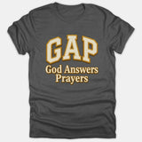 A dark gray t-shirt featuring the word GAP in large collegiate letters above the text God Answers Prayers printed in beige with gold outlines.