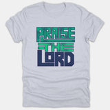 A light gray Christian t-shirt featuring bold block lettering that reads 'PRAISE THE LORD' in green and navy blue.