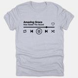 A gray Christian t-shirt featuring a black music player graphic with the song title Amazing Grace How Sweet The Sound and audio controls.