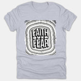 A light gray t-shirt featuring a graphic print with the text FAITH OVER FEAR centered inside distressed concentric wave patterns in black, white, and gray.