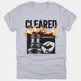 A light gray t-shirt featuring a graphic design of a hand holding a judge's gavel, orange flames, and text referencing Romans 8:1.