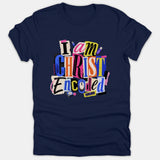 A navy blue t-shirt featuring a colorful, ransom-note style typography graphic that reads 'I am CHRIST Encoded' with tech-inspired icons.
