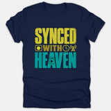 Navy blue t-shirt featuring the distressed text SYNCED WITH HEAVEN printed in bold yellow and teal graphic lettering alongside live broadcast icons.