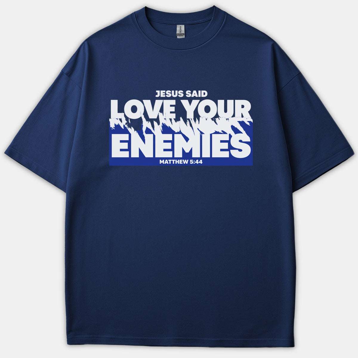 A navy blue Christian t-shirt featuring bold white typography that reads 'JESUS SAID LOVE YOUR ENEMIES MATTHEW 5:44' across a distressed blue graphic background.