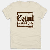 A beige Christian t-shirt featuring a dark brown graphic frame with the text Count it all joy and the bible verse James 1:2.