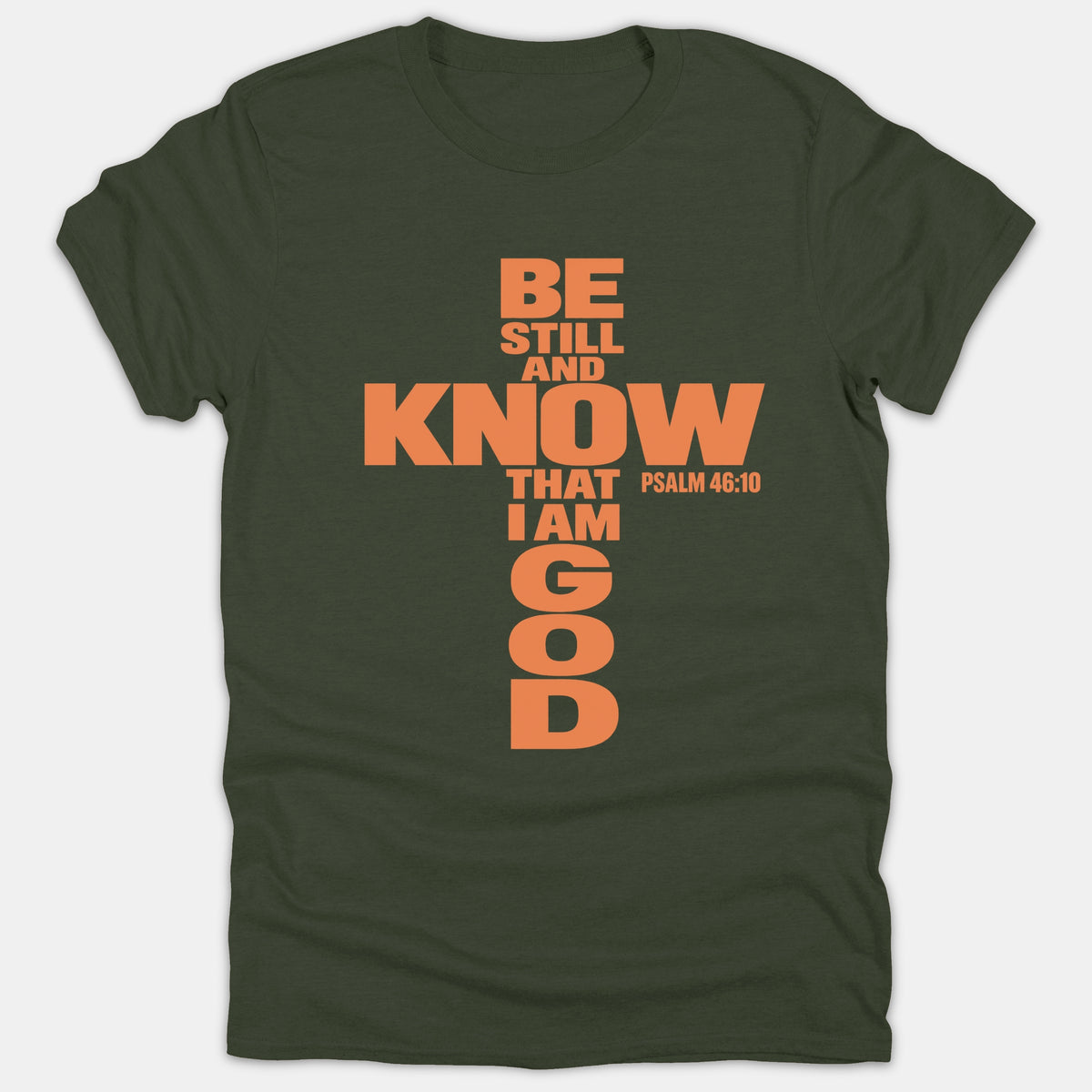 A dark green Christian T-shirt featuring the scripture phrase 'Be Still And Know That I Am God' from Psalm 46:10 arranged in the shape of a cross.