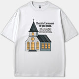 A white graphic T-shirt featuring an illustration of a church with glowing windows alongside text reading, 'Church isn’t a museum for good people. It’s a hospital for the broken.'