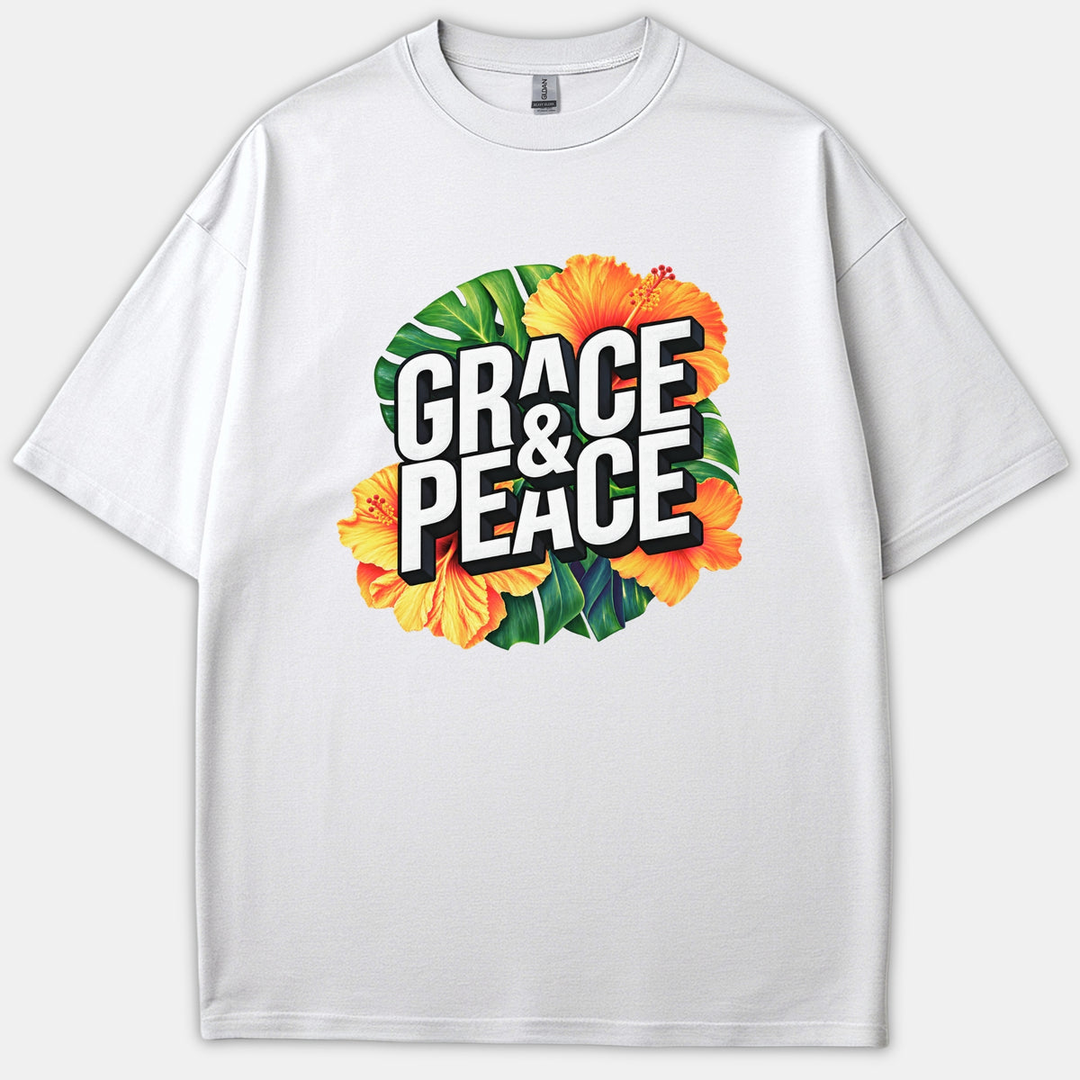 A white Christian t-shirt featuring bold text reading GRACE & PEACE displayed over vibrant tropical yellow hibiscus flowers and green leaves.