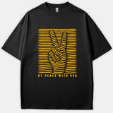 A black t-shirt featuring a yellow optical illusion peace sign hand graphic with the phrase AT PEACE WITH GOD printed below.