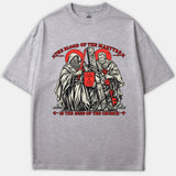 A gray t-shirt featuring a detailed Christian graphic of Saints Paul and Peter in red and black ink with the text 'The Blood of the Martyrs is the Seed of the Church'.