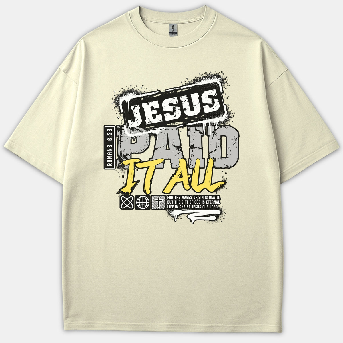 A beige graphic t-shirt featuring urban street-style typography that reads 'Jesus Paid It All' with a Romans 6:23 scripture reference in black, gray, and yellow distressed print.