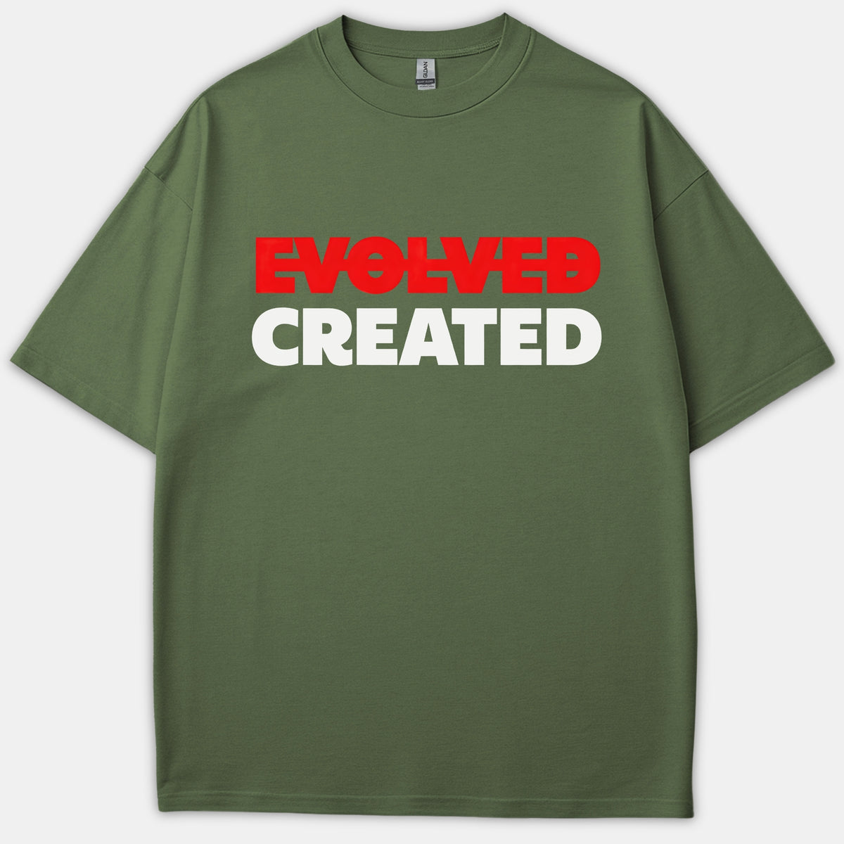 An olive green Christian t-shirt featuring the word EVOLVED crossed out in red above the word CREATED printed in bold white text.