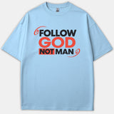A light blue t-shirt featuring the bold Christian phrase 'FOLLOW GOD NOT MAN' printed prominently across the chest in red and black lettering.