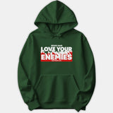 A dark green hoodie featuring a bold graphic reading 'Jesus Said Love Your Enemies Matthew 5:44' in white and red text across the chest.
