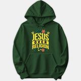 A dark green hoodie featuring the phrase 'JESUS OVER RELIGION' in bold yellow typography surrounded by colorful floral accents.