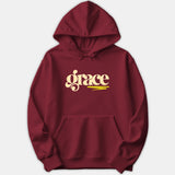 A maroon red hoodie featuring the word grace printed in a retro cream typography with a yellow brushstroke underline.
