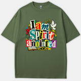 An olive green Christian t-shirt featuring colorful collage-style lettering reading 'I am Spirit anointed' surrounded by Christian symbols like a dove, cross, bible, and ichthys fish.