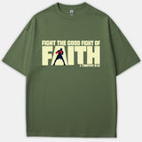 An olive green t-shirt featuring the graphic text 'FIGHT THE GOOD FIGHT OF FAITH' with a boxer silhouette cut out inside the word 'FAITH' and 1 Timothy 6:12 printed below.