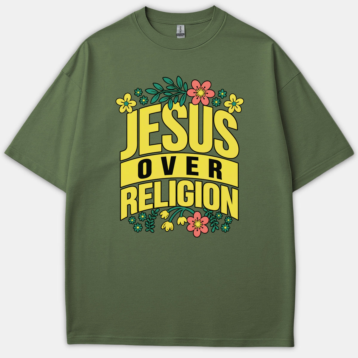An olive green t-shirt featuring bold yellow typography that reads 'JESUS OVER RELIGION' framed by colorful floral and botanical illustrations.
