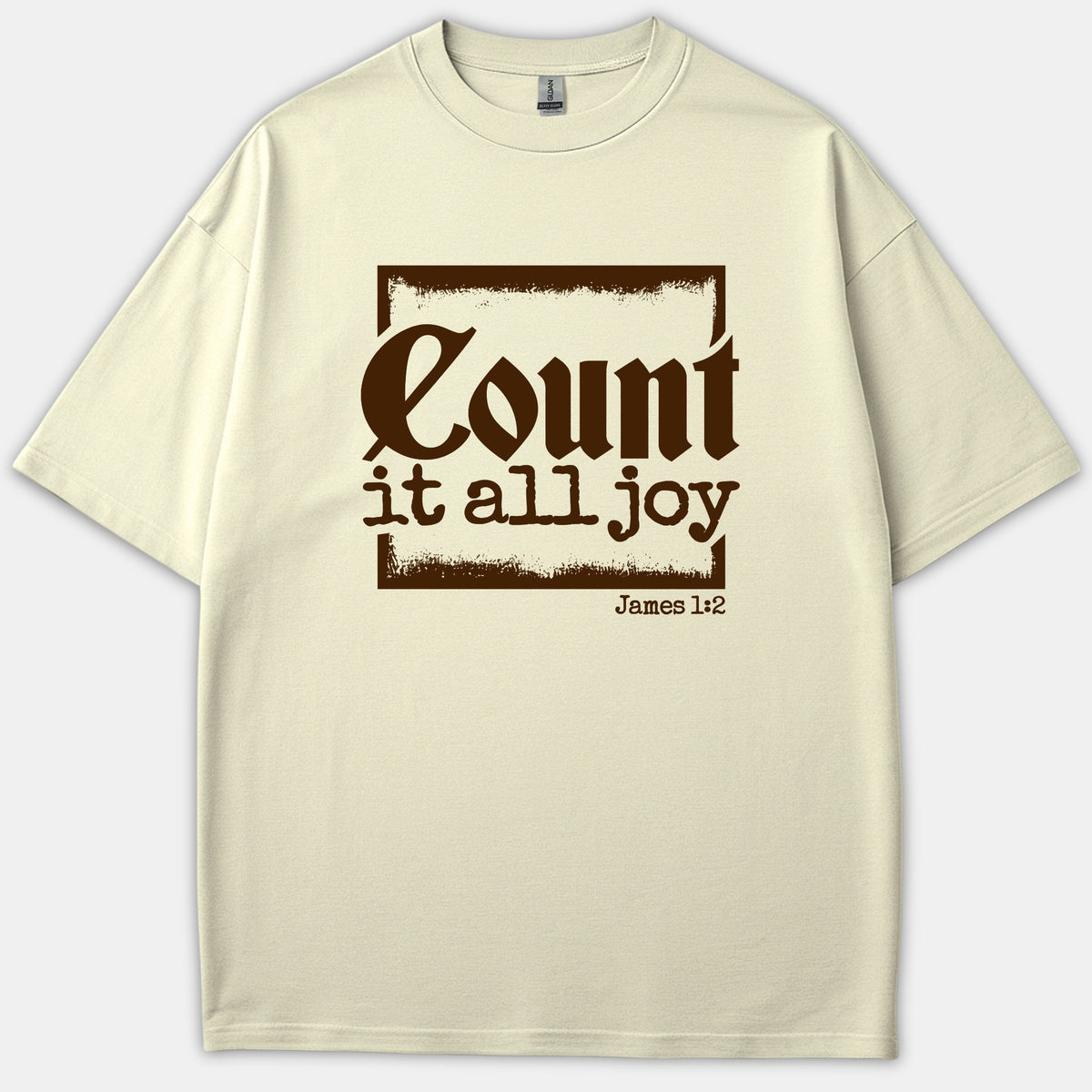 A beige t-shirt featuring a brown distressed square frame with the Bible verse phrase Count it all joy and James 1:2 printed in stylized text.
