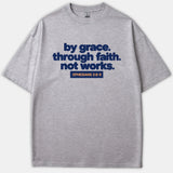 A heather gray t-shirt featuring navy bold text reading 'by grace. through faith. not works.' above a navy block with orange text that reads 'EPHESIANS 2:8-9'.