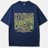 A navy blue Christian t-shirt featuring a yellow ornate swirly design with the word FORGIVEN in green, a cross emblem, and Micah 7:19 scripture.