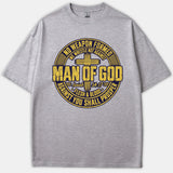 A gray Christian T-shirt featuring a circular distressed graphic with a cross, reading 'Man of God' and referencing Isaiah 54:17.