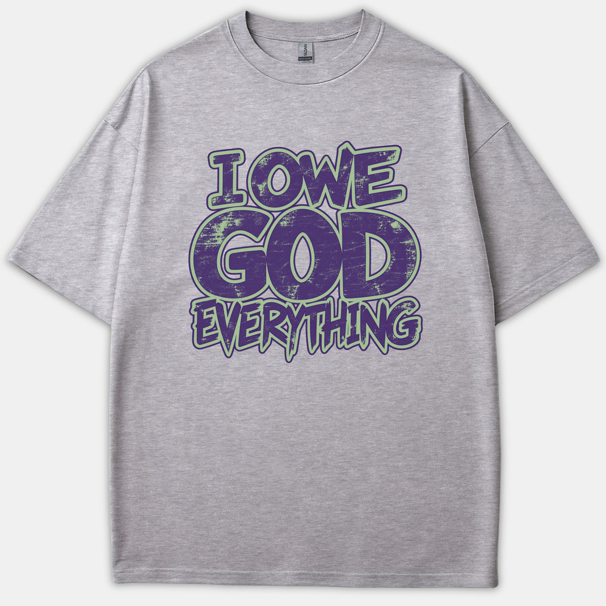 A gray t-shirt featuring the text 'I OWE GOD EVERYTHING' in a distressed purple font outlined in green.